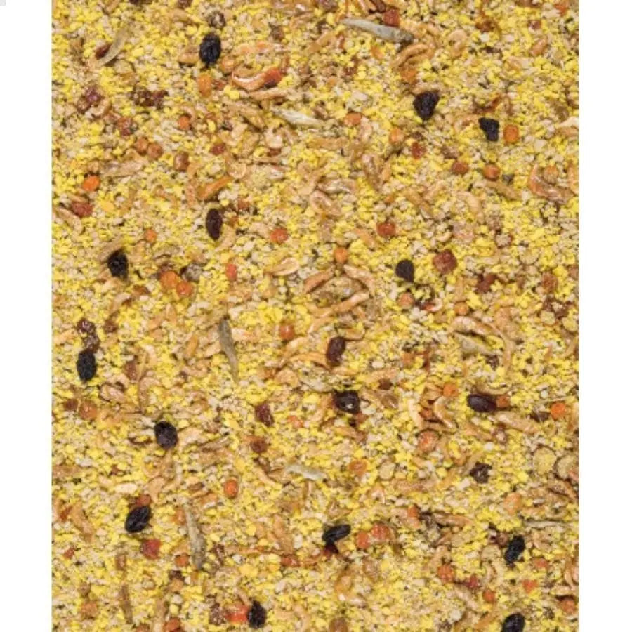 Gros plan sur Orlux Pâtée Sèche Grandes Perruches et Perroquets - 800gr, mettant en valeur le millet jaune, les petits grains, les graines de tournesol, le maïs séché et les raisins secs noirs. Idéal pour les perroquets et les grandes perruches avec sa texture variée en tailles, formes et couleurs.